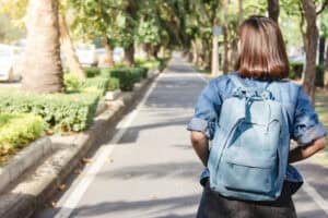 Female student wearing a backpack walking on a college campus in the Sarasota area