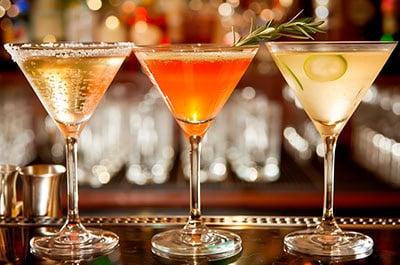 Fancy cocktails in martini glasses sitting on top of an upscale bar