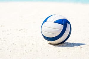 Blue and white volleyball sitting on white sand of Siesta Key Beach