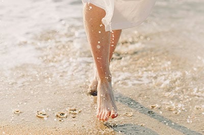 Woman walking barefoot on the beach